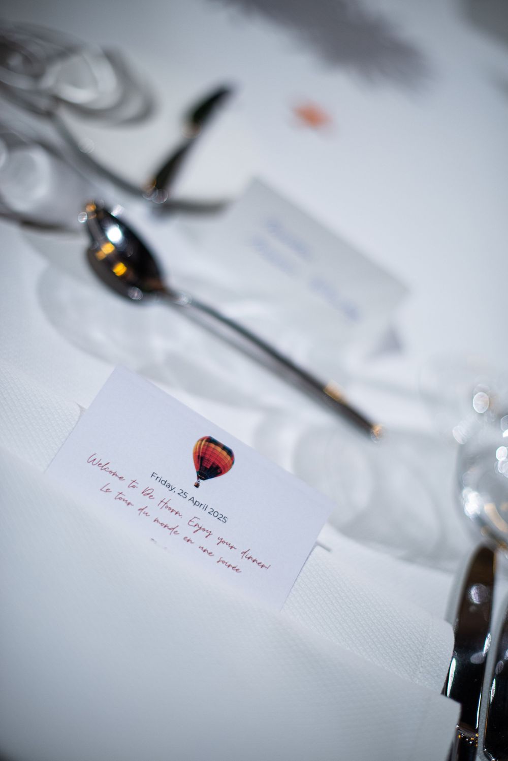 Place settings with wine glass markers and handwritten notes on white tablecloths.