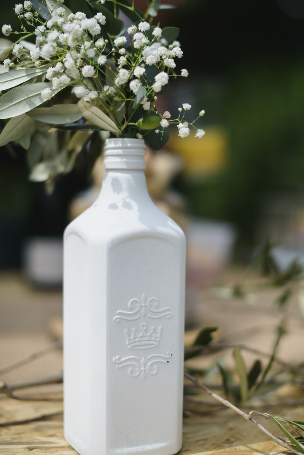 White ceramic milk bottles with delicate baby's breath flowers arranged on rustic surface.