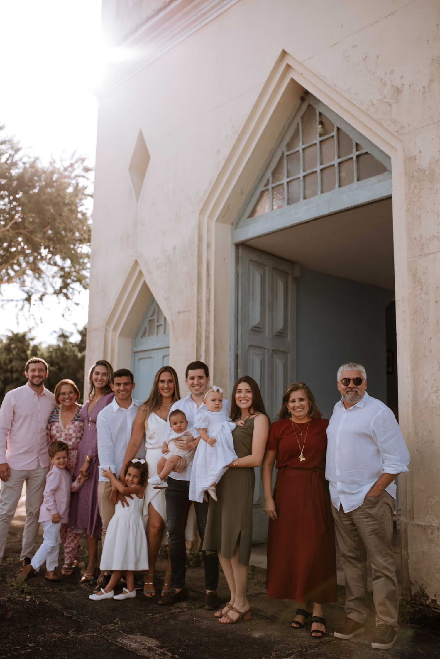 Extended family gathering outside church entrance for baptism celebration.