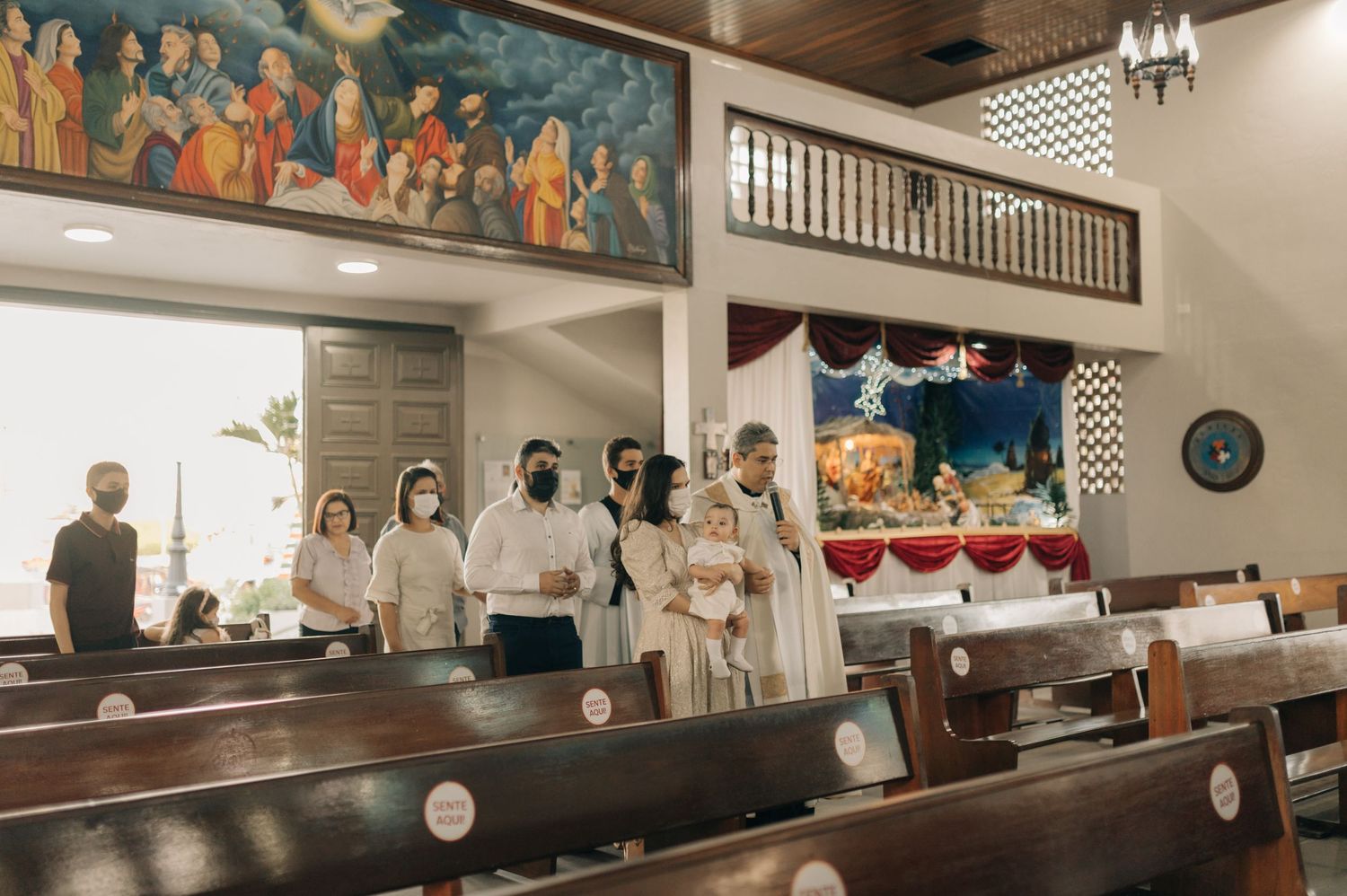 People gather in a church interior with religious artwork and wooden pews visible.