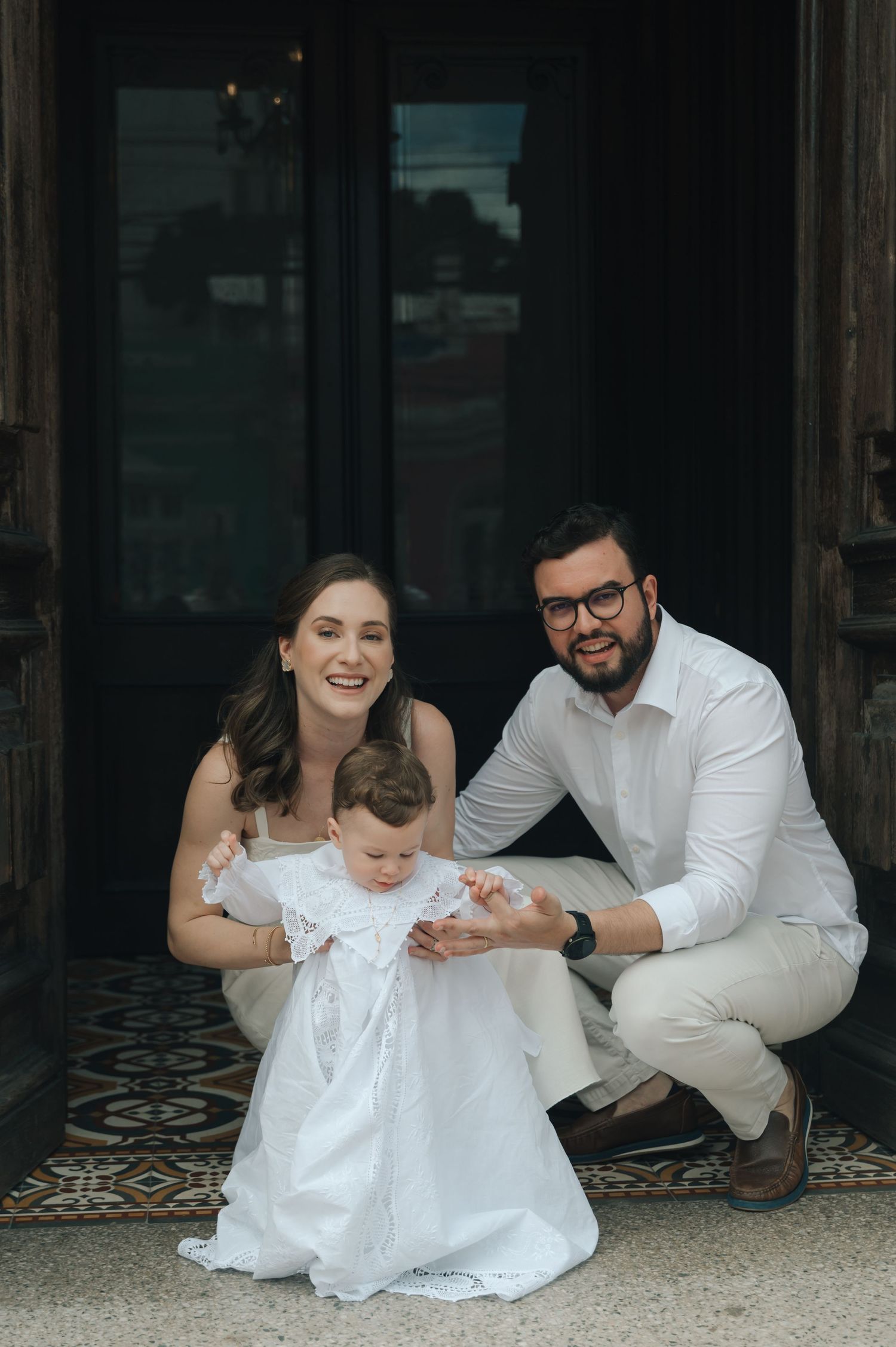 A family gathers for a portrait in formal attire on ornate tiled floor.
