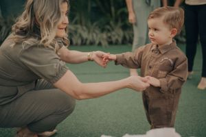 A tender moment of interaction between adult and child on green turf in warm earth tones.