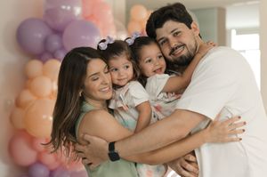 A loving family embraces during a celebration with colorful balloons in the background.