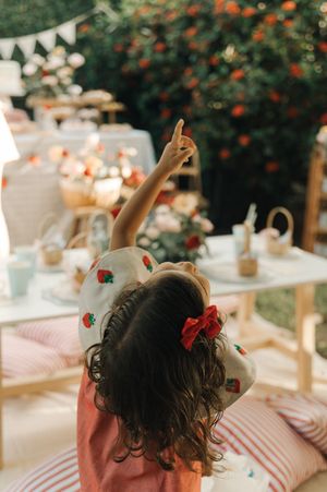 Red floral decorations and bunting adorn a dreamy garden party table setting with soft natural lighting.
