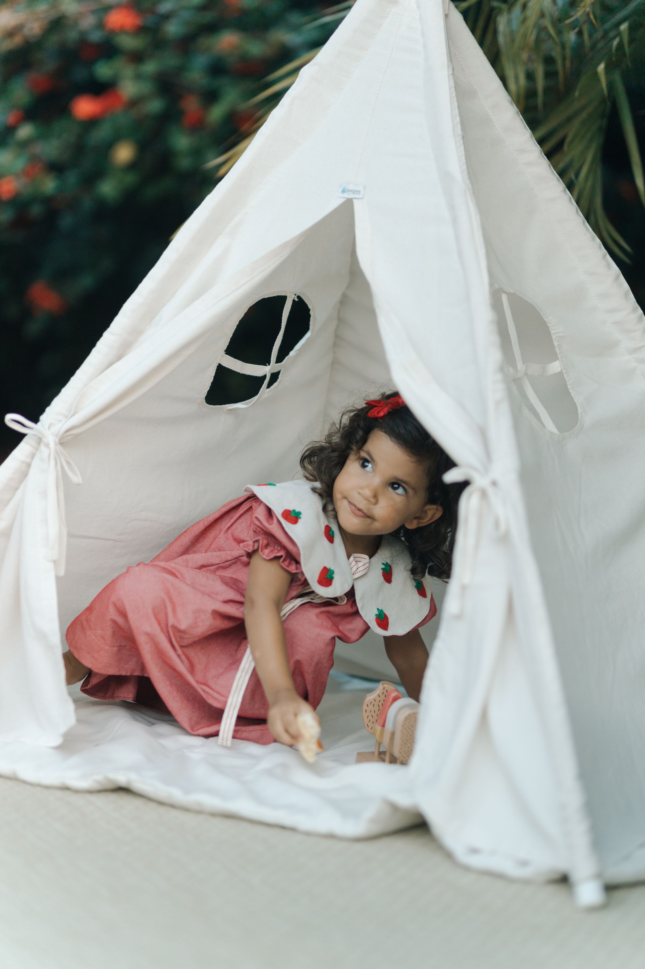 A white teepee tent with a small decorative logo sits against a green background.