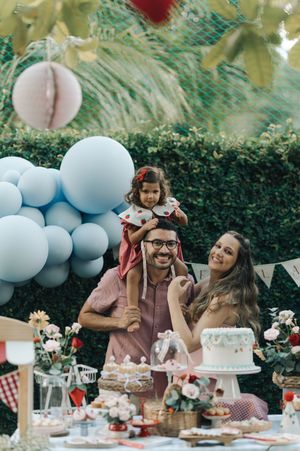 A festive outdoor celebration with blue balloon decorations, dessert table, and family gathering in a garden setting.
