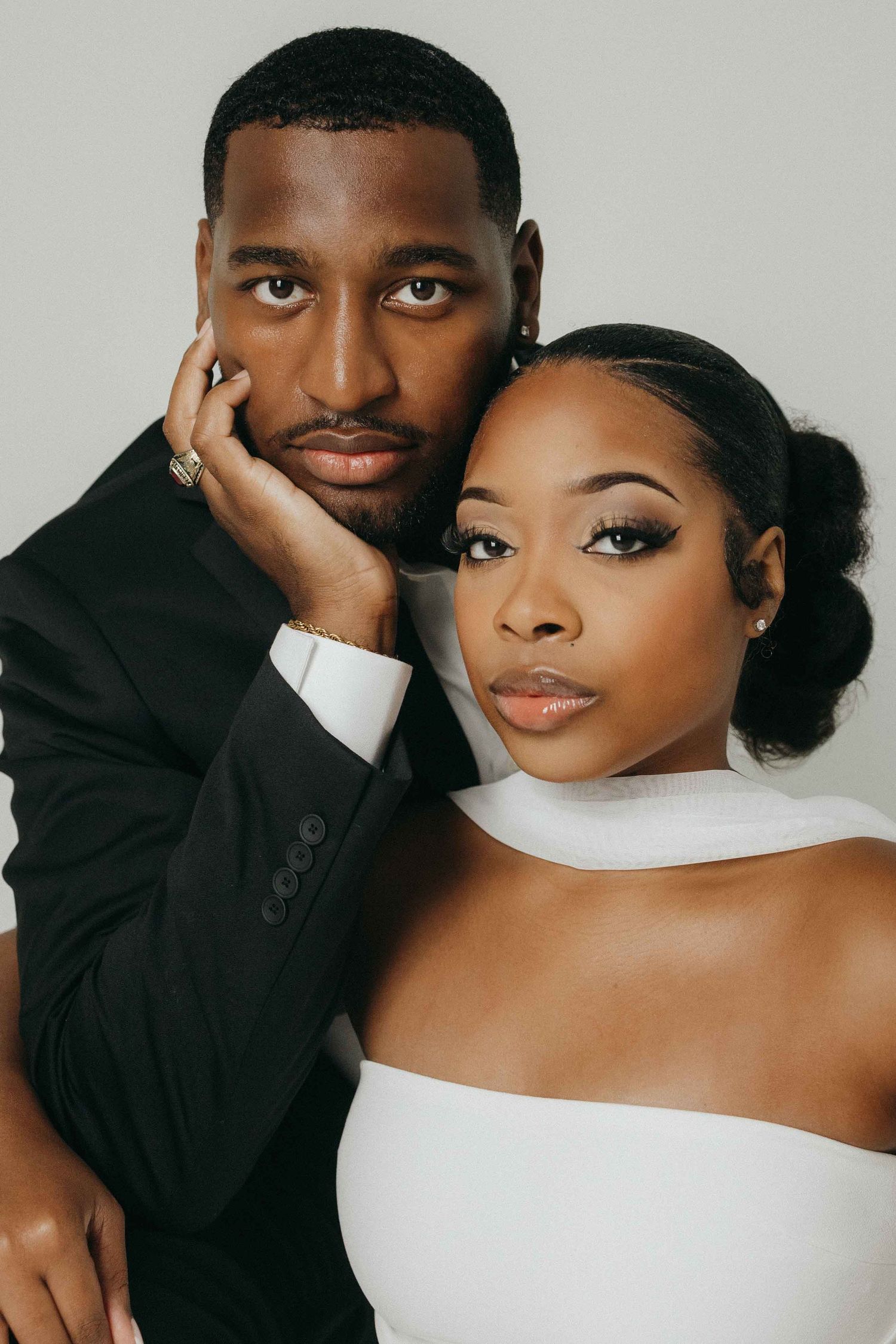 Elegant couple in formal black and white attire posing for intimate portrait.