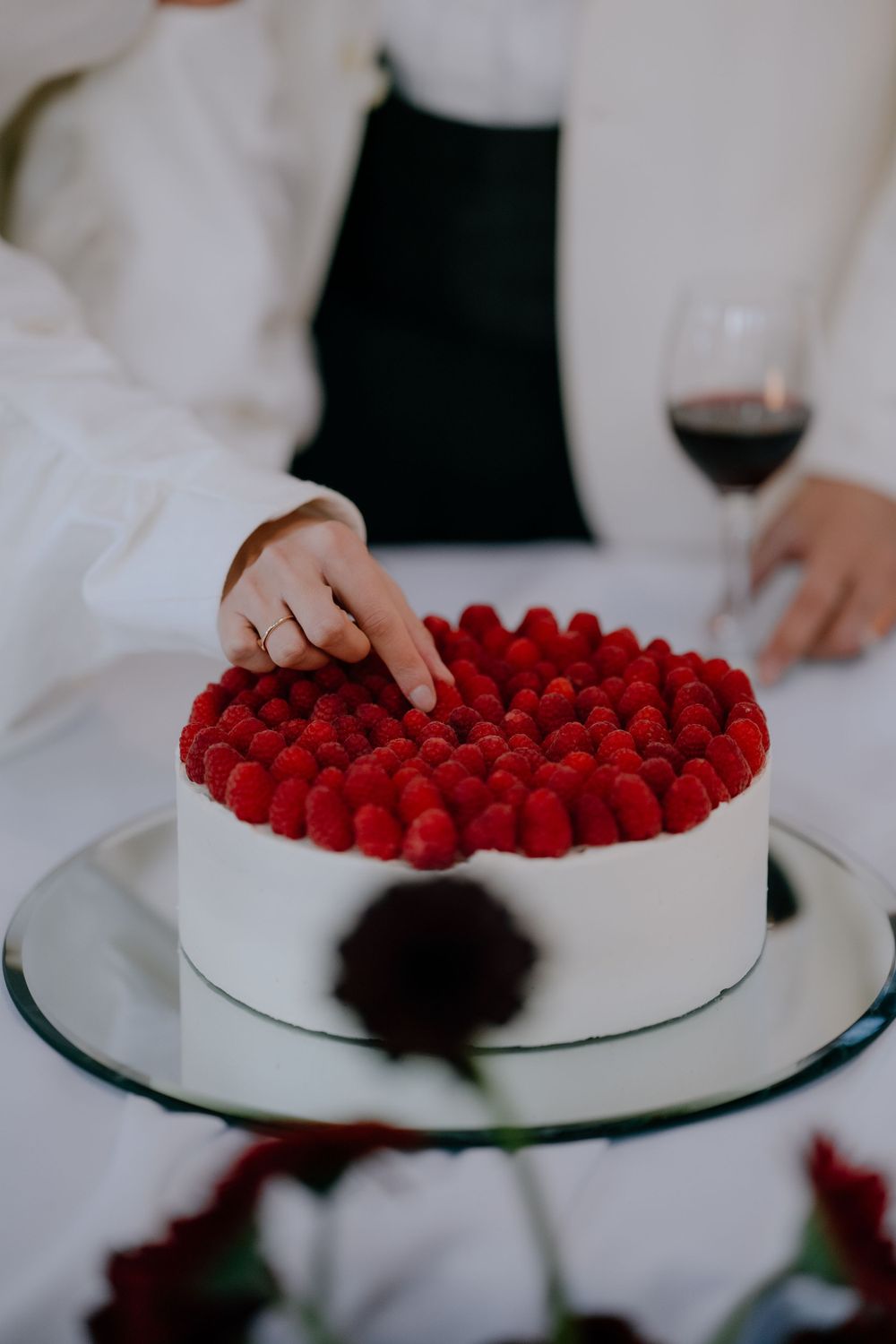 White cake decorated with fresh red raspberries being served at formal event.