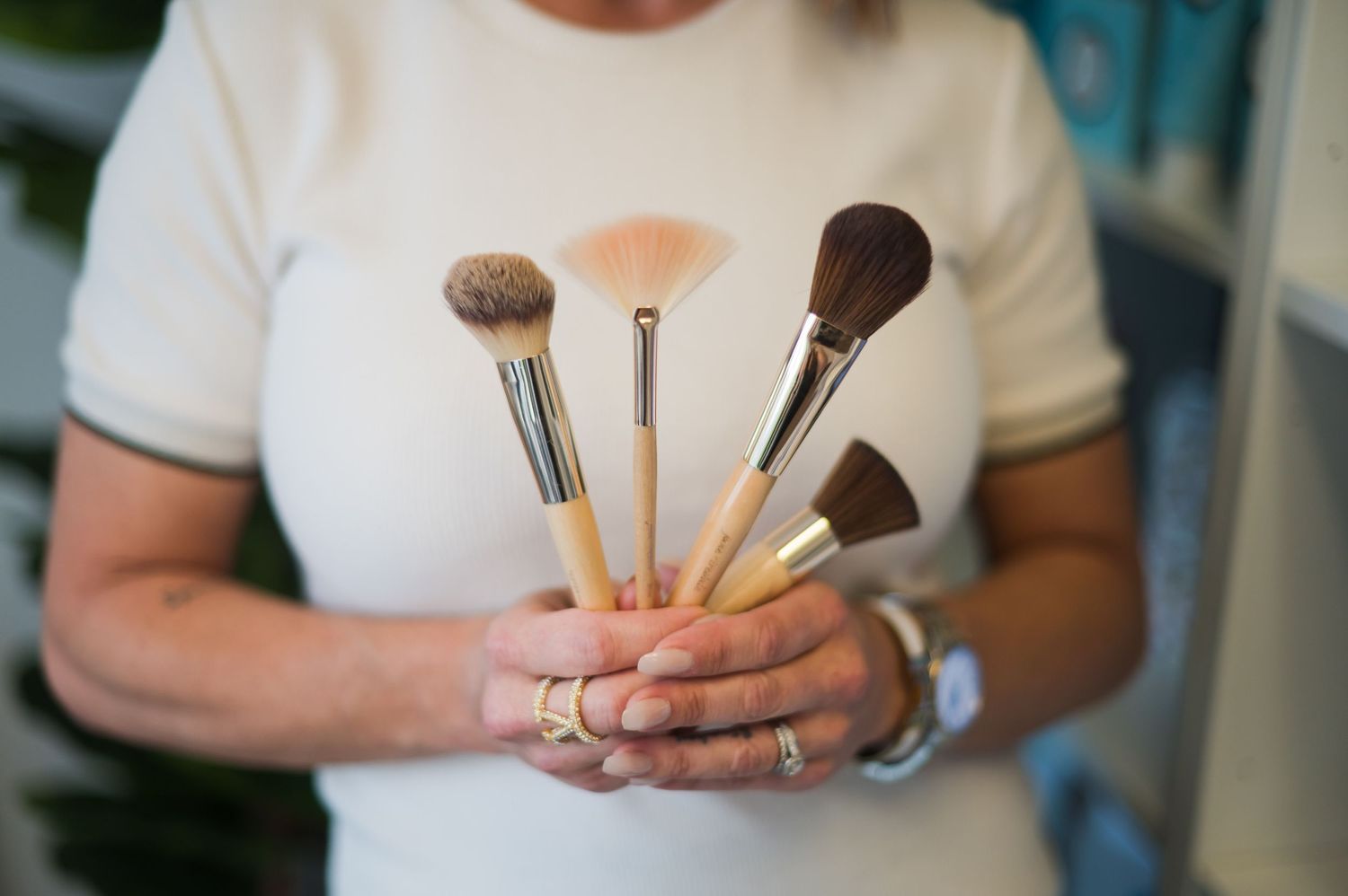 Close-up of hands holding multiple makeup brushes.