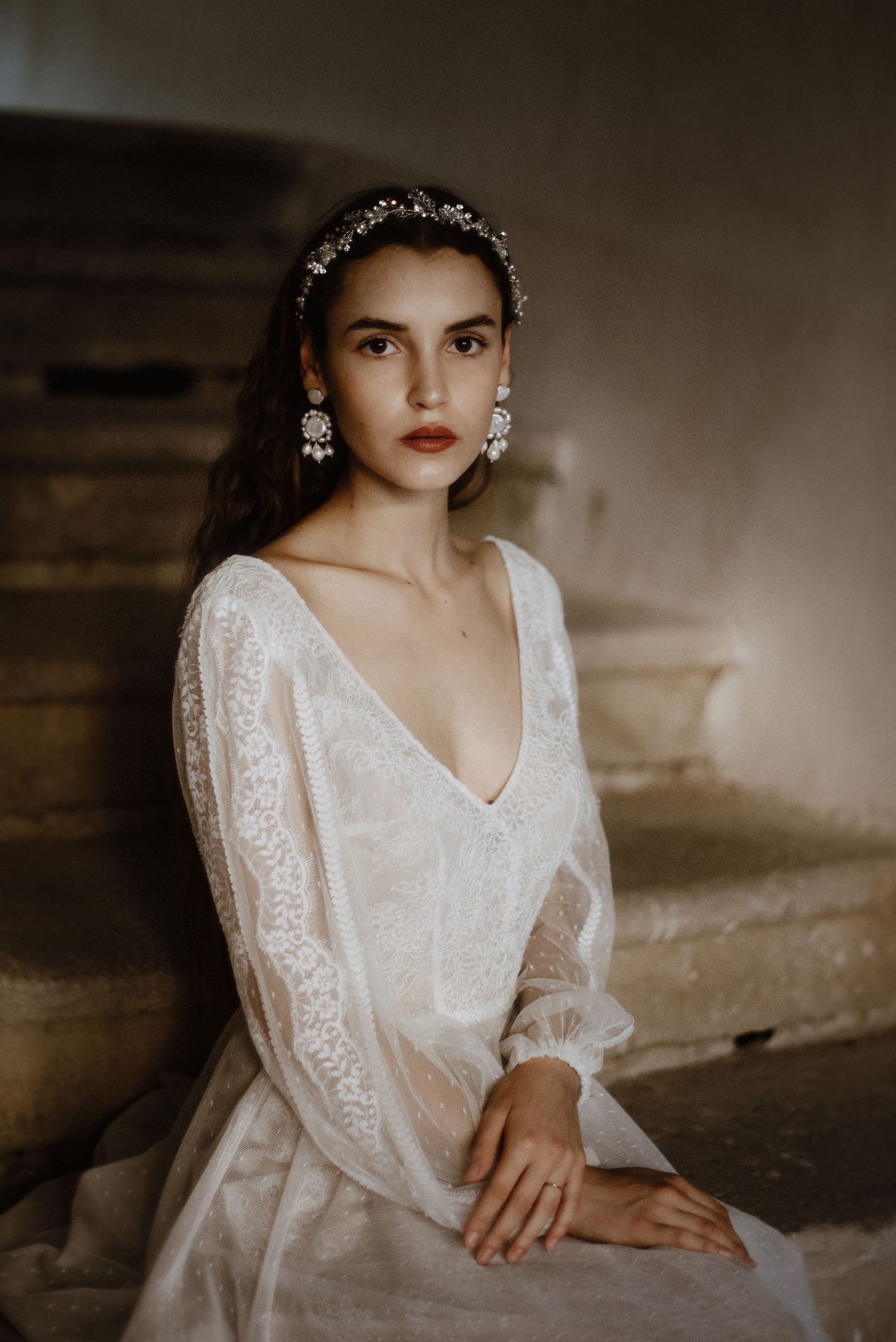 Moody artistic portrait series featuring white bridal gown and floral crown headpiece against shadowy backdrop.