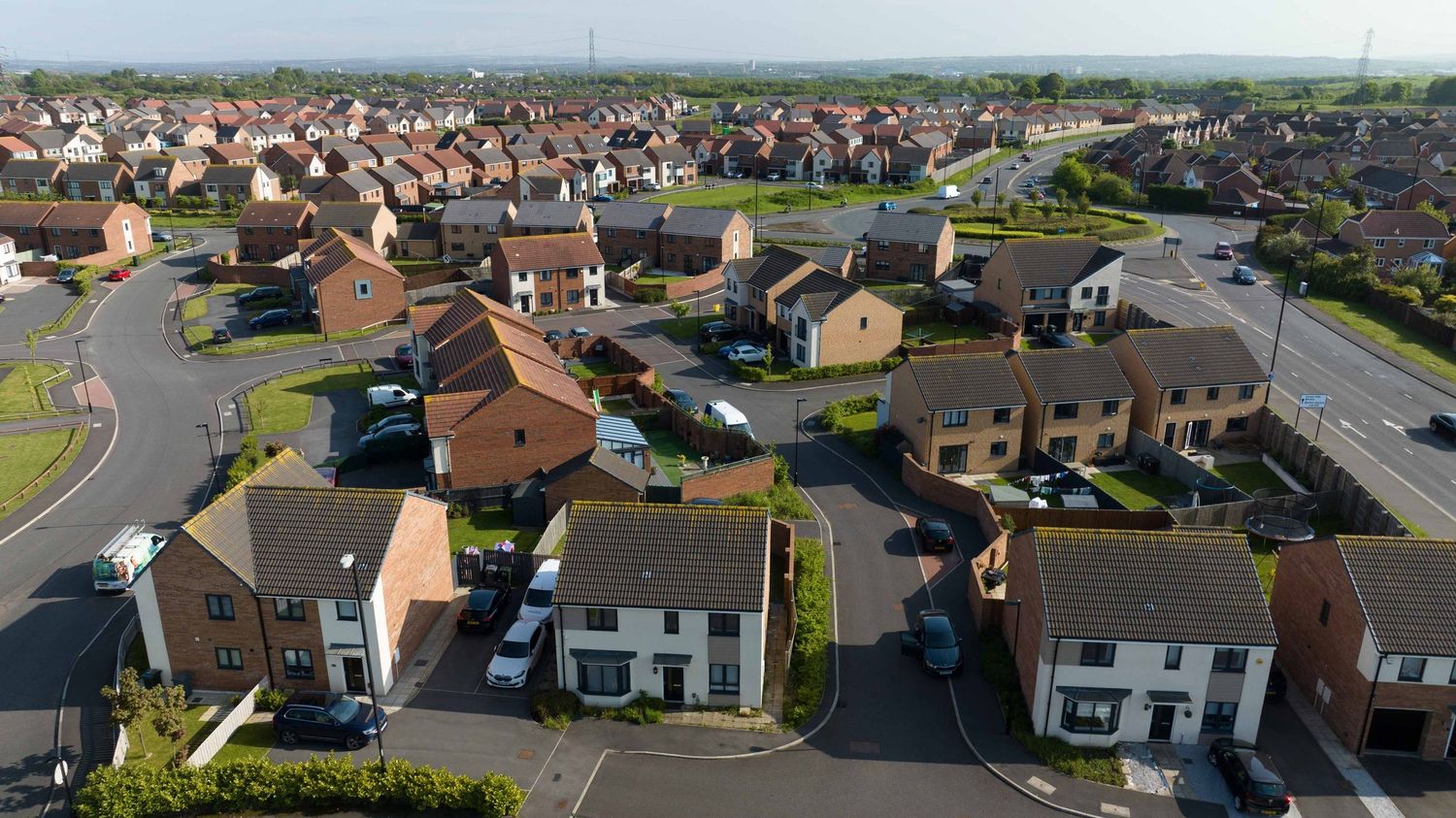 Aerial view of a modern residential housing estate with curved roads and detached homes in a suburban neighborhood.