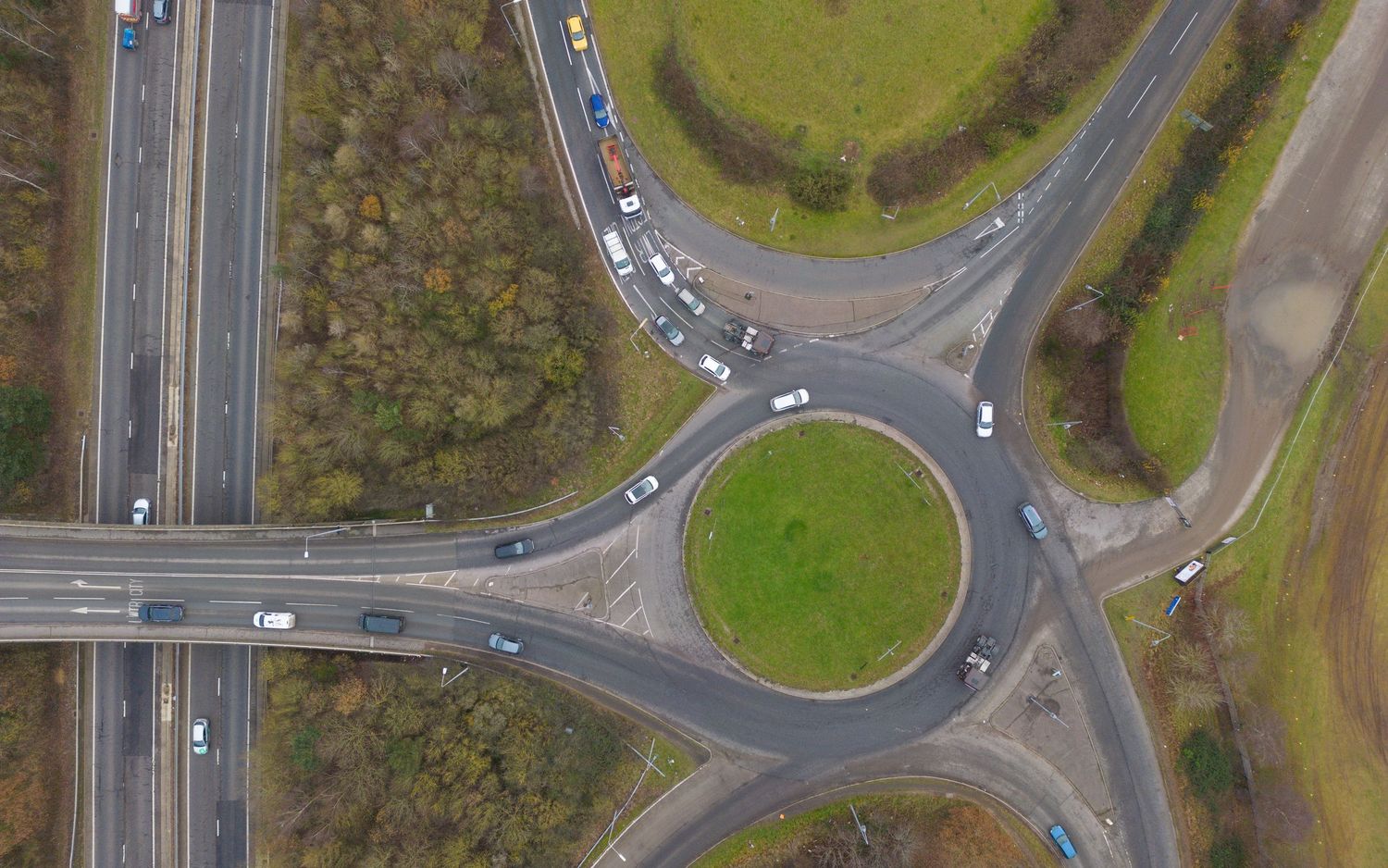 Aerial view of a circular roundabout intersection with traffic and grassy center median on a highway interchange.