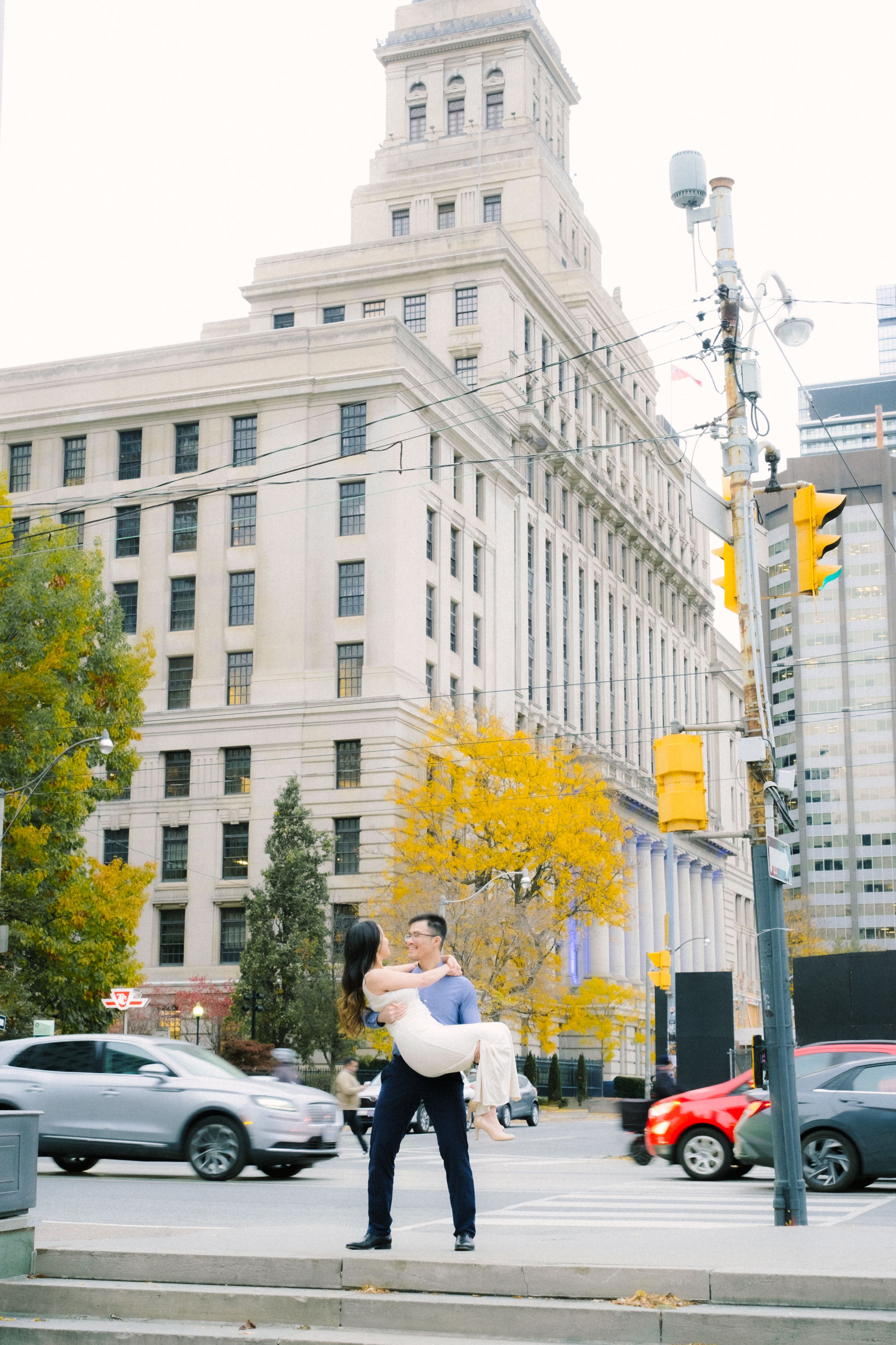 Romantic lift pose in front of historic downtown building with fall foliage.