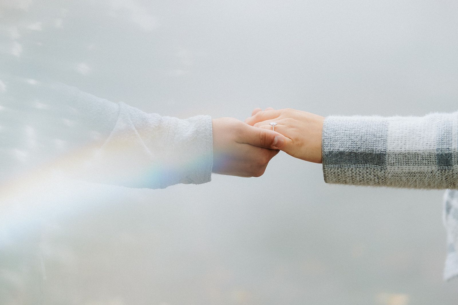 Two people holding hands with a dreamy, ethereal light effect in the background.
