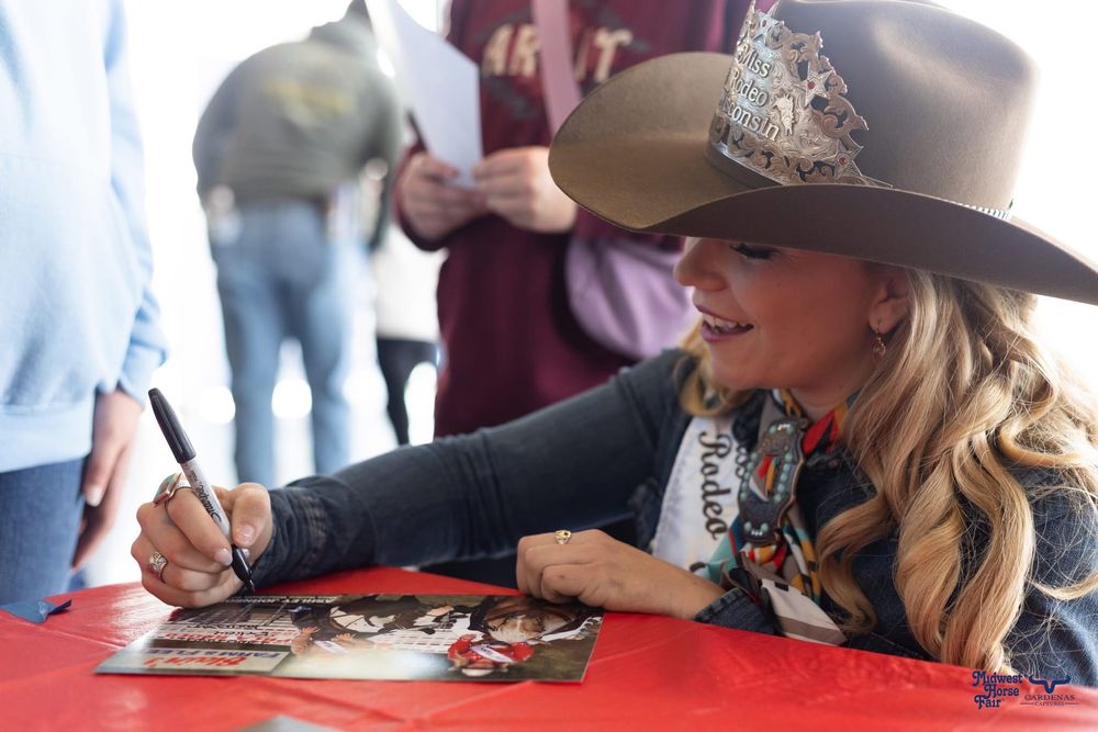 People in western attire signing autographs at a table. Wisconsin Pro Rodeo PRCA Rodeo Photographer Dakota Cardenas