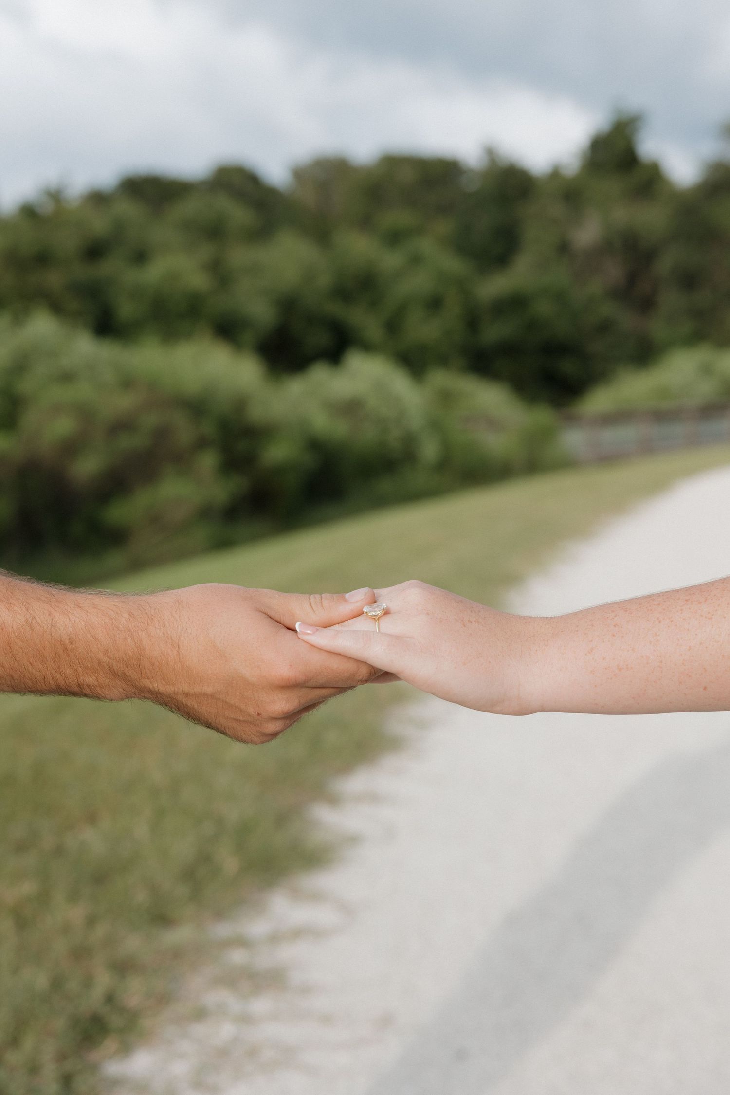 Hands reaching out to connect along a scenic outdoor path surrounded by greenery.
