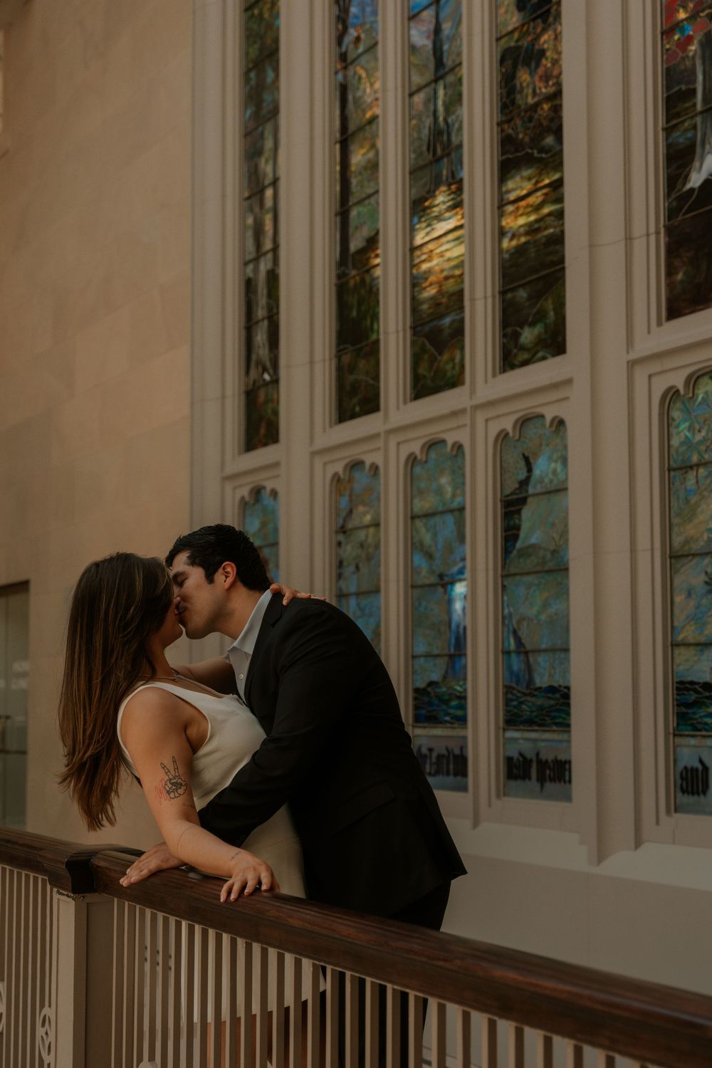 Romantic moment captured in front of towering stained glass windows and ornate architecture.