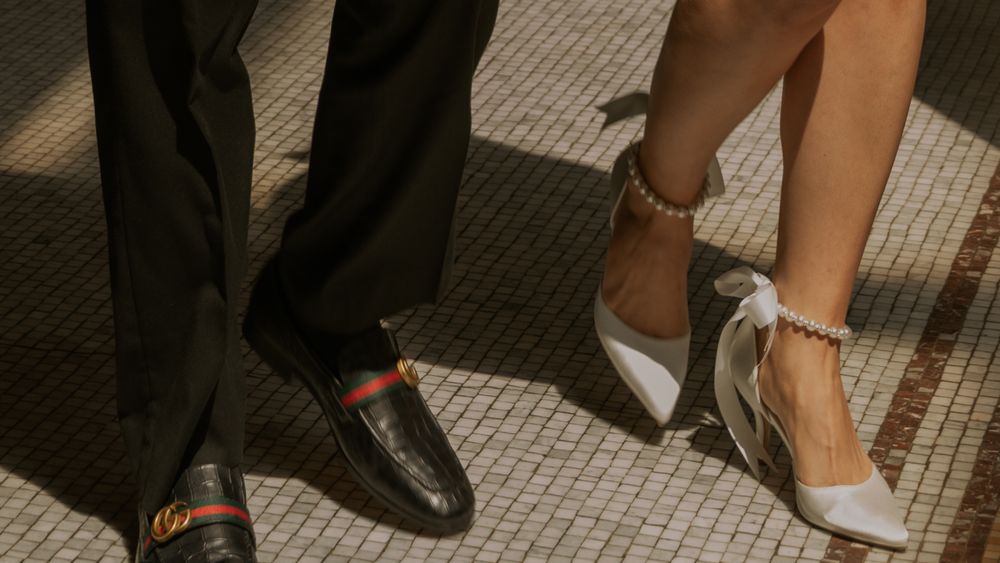 Formal footwear detail showing elegant heels and dress shoes on a tiled floor.