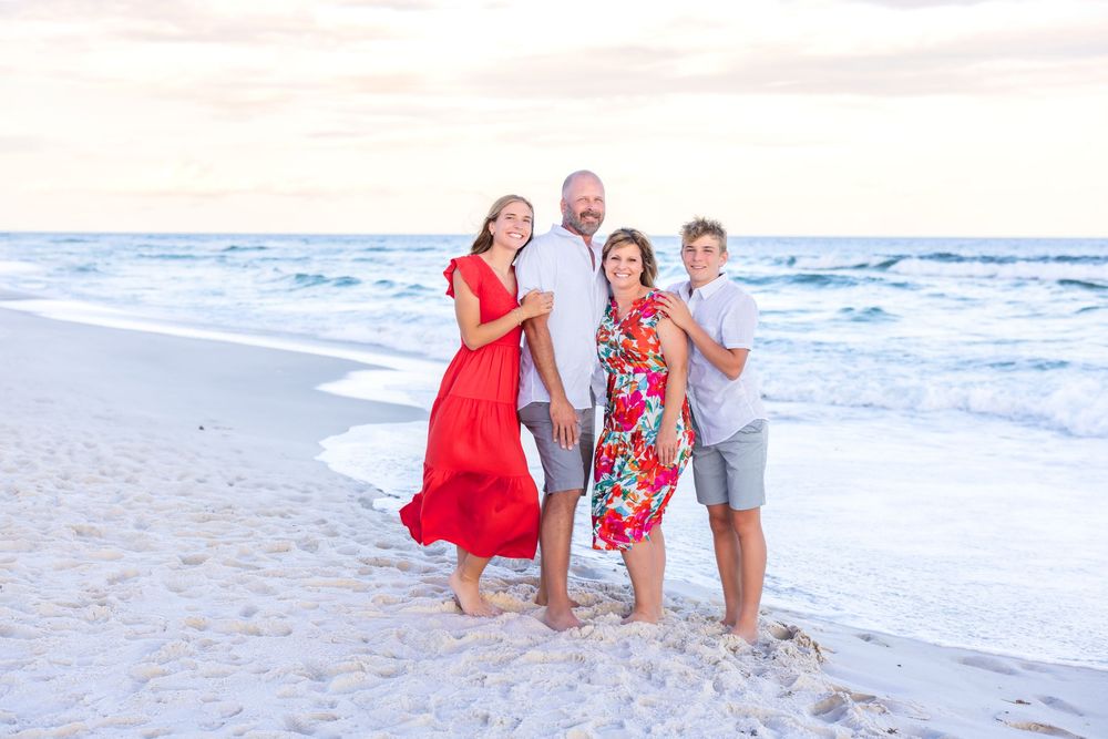 A group enjoying their time together walking along a sandy beach with ocean waves in the background.