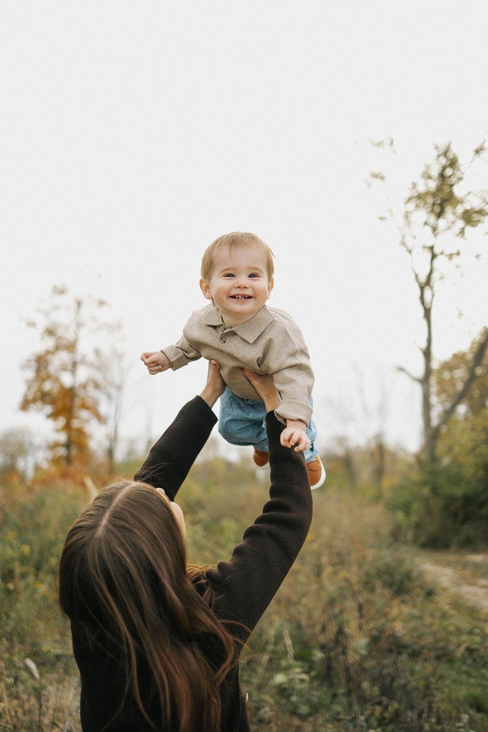 A series of four photos showing a child being playfully lifted up into the air outdoors during autumn.