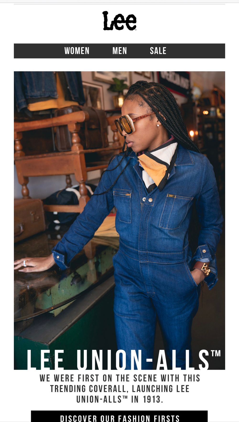 Denim workwear promotional banner shows models wearing dark blue Lee Union-Alls coveralls in industrial setting.