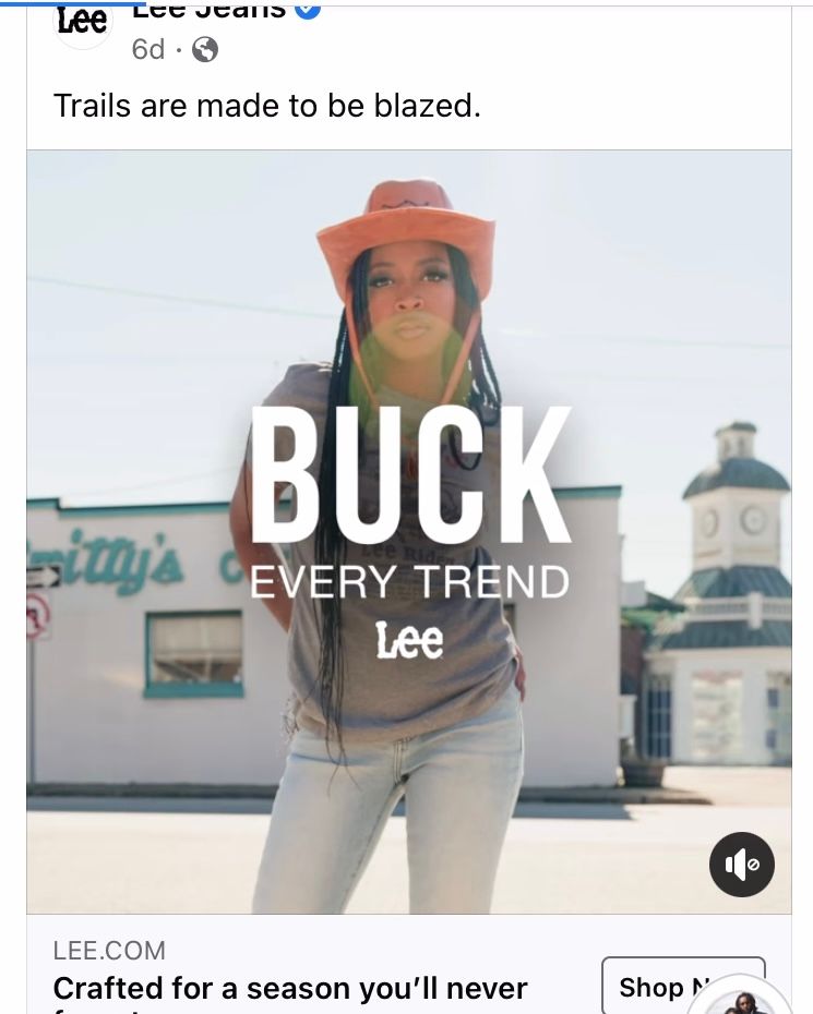 Lee Jeans advertisement showing someone in denim and orange hat with text saying 'BUCK EVERY TREND' on urban backdrop.