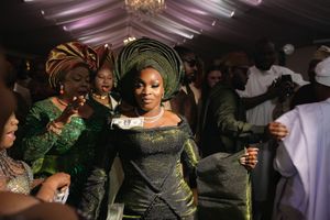 Wedding celebration with energetic dancers and party guests enjoying festivities on a dance floor beneath a chandelier.