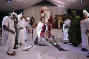 People in white and colorful traditional attire gather on a dance floor during a festive cultural celebration.