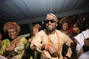 Joyful celebration at a Nigerian wedding reception with guests in traditional attire dancing and smiling.