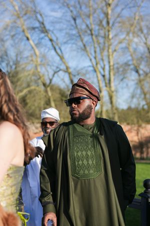Person wearing traditional African attire and sunglasses at outdoor social event.