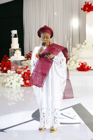 Wedding reception setup with burgundy decor, white tablecloths, and red floral arrangements on a pristine white table.