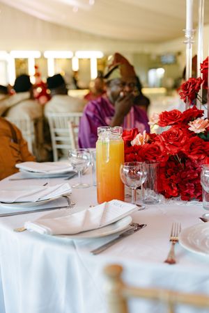 An elegant table setting with red roses and orange juice for a formal dining event.