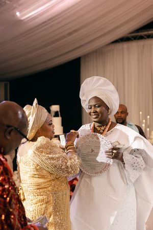 Joyful moment at a traditional Nigerian wedding ceremony with guests wearing elegant gold and white attire.
