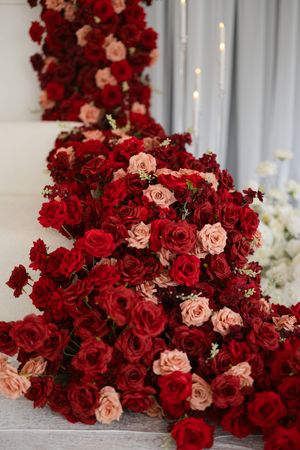 Luxurious floral arrangement featuring deep red roses mixed with blush pink roses cascading down against a light backdrop.