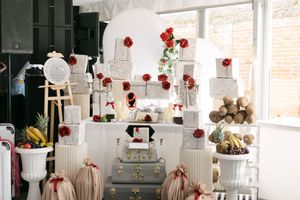A whimsical white display setup with red roses and vintage decor elements in a bright retail space.