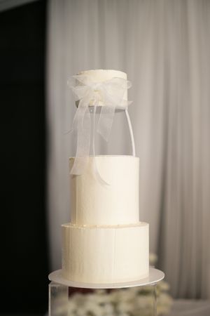 A series of white wedding cakes being assembled showing various stages of stacking and preparation with tulle decorations.