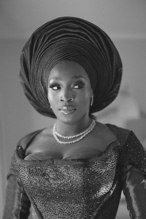 Black and white portrait showing traditional Nigerian glamour with gele headwrap, pearl necklace and ornate dress.