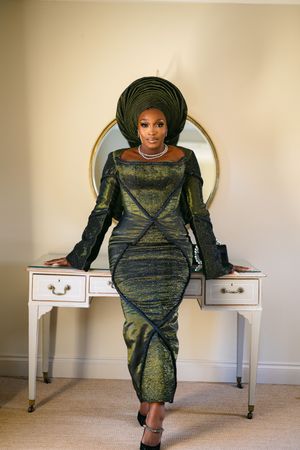 Elegant green and black shimmering dress with bell sleeves and matching head wrap, posed against white vintage vanity.
