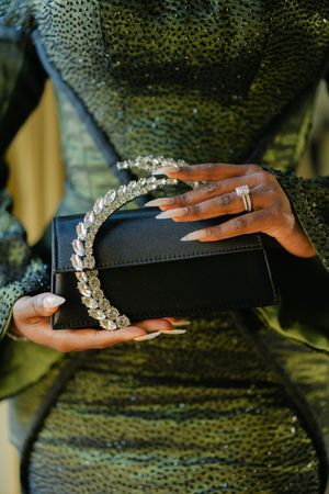 Close-up shots of hands wearing rings and bracelets with crystal details against a dark textured background.