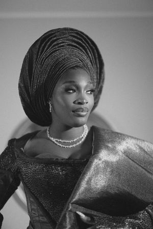 Elegant portrait in black and white featuring traditional African gele headwrap and formal attire.