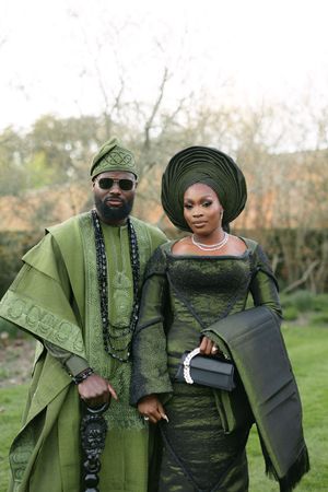 Traditional Nigerian wedding attire in matching green and black fabrics with gele and agbada.