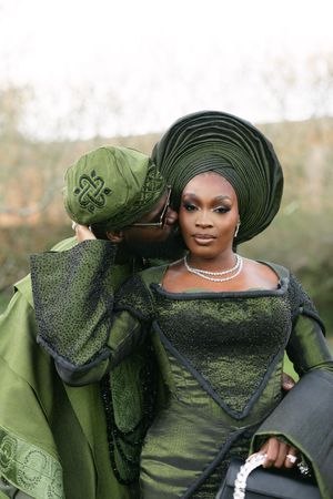 Traditional Nigerian formal attire in olive green with elaborate gele headwrap and diamond jewelry.
