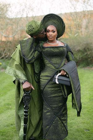 Elegant couple in matching dark green traditional African clothing with ornate headwear.