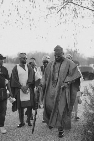A vintage black and white photograph showing a group of people wearing traditional robes and headwear outdoors.