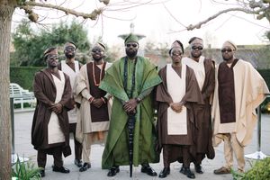 A group in traditional African-inspired formal attire featuring brown and cream robes with green accents.