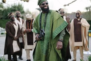 Person wearing an elegant emerald green agbada with traditional embroidery at an outdoor event.