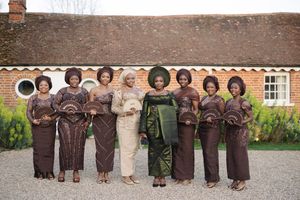 Group photo showing coordinated traditional African attire in brown and olive green tones against brick building.