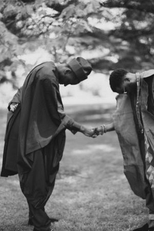 Black and white photo of two people in formal attire greeting each other.