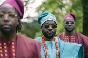 Close portrait of traditional African fashion featuring coral beads and embroidered turquoise headwear.