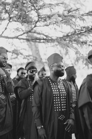 Black and white portrait of group wearing patterned traditional clothing and sunglasses.